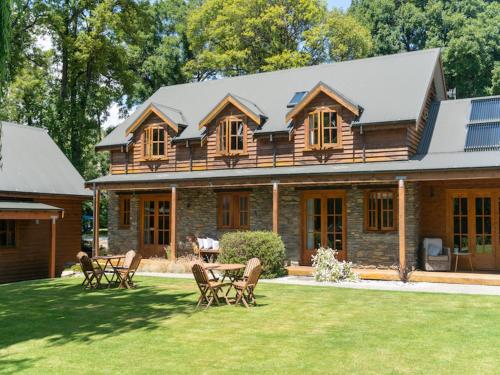 a log home with a table and chairs in the yard at Wanaka Homestead Lodge & Cottages in Wanaka