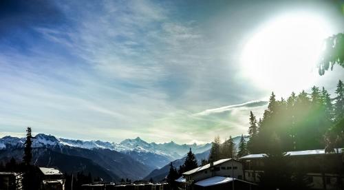 a view of a mountain with the sun in the sky at Crans Luxury Lodges in Crans-Montana