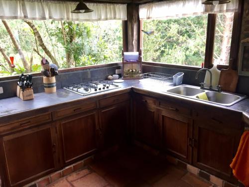 cocina con armarios de madera, fregadero y ventana en El Cobijo, en Chocontá