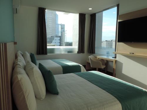 a hotel room with two beds and a large window at Hotel Plaza Sol Veracruz in Veracruz