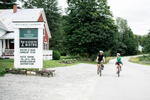 two people riding bikes down a road next to a sign at Craftsbury Farmhouse in Craftsbury