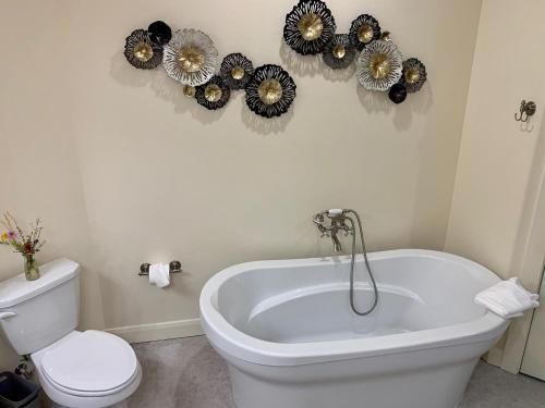 a bathroom with a tub and a toilet and flowers on the wall at Annie's Place Bed & Breakfast in Boulder Town