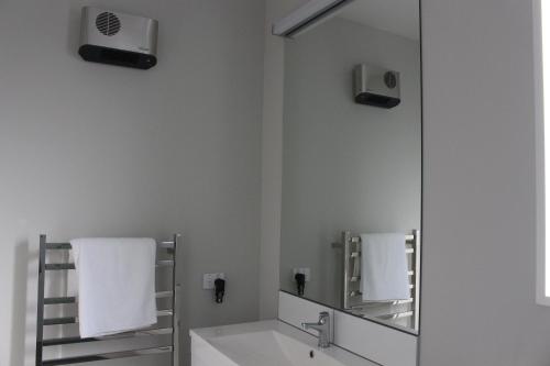 W białej łazience znajduje się umywalka i lustro. w obiekcie Fivestone Suite w mieście Lake Tekapo