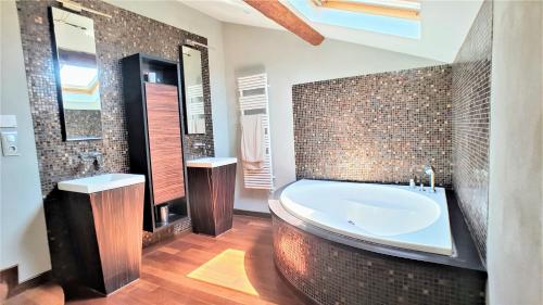 a bathroom with a large tub and a tile wall at Appart'hôtel Luxe Vieil Antibes 75 m2 avec Parking plages à pieds in Antibes