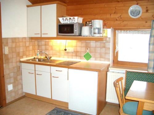a small kitchen with a sink and a microwave at Haus Schneeberg mit Hochkönig Card in Mühlbach am Hochkönig