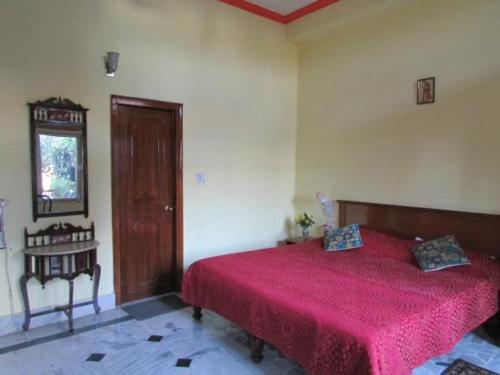 a bedroom with a bed with a red bedspread at Hotel Zen in Khajurāho