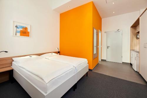 a bedroom with a white bed and an orange wall at Townhouse Düsseldorf in Düsseldorf