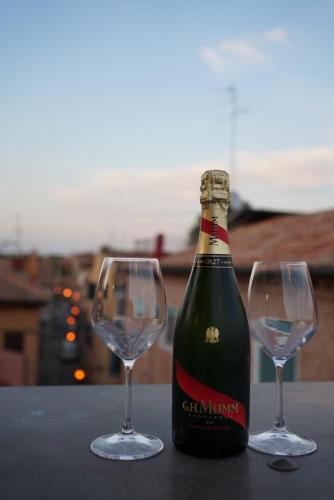 a bottle of champagne and two wine glasses on a table at Green Rooms Ferrara in Ferrara