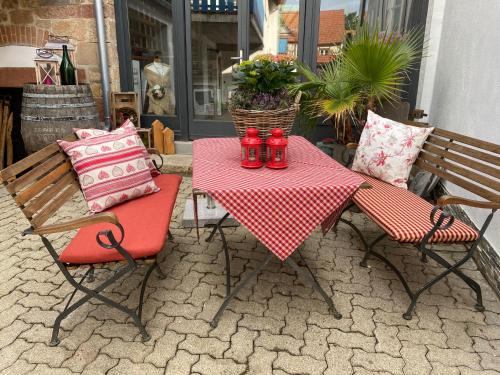 a table and two chairs with a red and white table cloth at Gästehaus Sellemols Ferienwohnung Korbmacher in Heuchelheim-Klingen