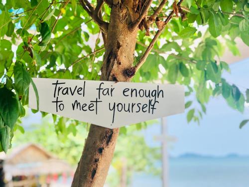 a sign on a tree that reads travel far enough to meet yourself at Indie Beach Bungalows in Ko Chang