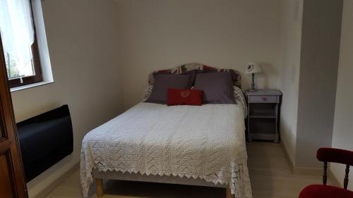 Habitación pequeña con cama con almohada roja. en Chambres d'hôte de Sauviolle, en Frontenac