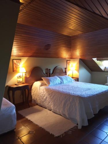 a bedroom with a bed and two lamps on two tables at Casa da Posta de Valmaior in Boiro