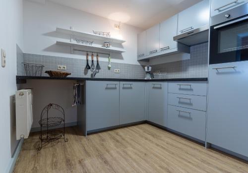 una cucina con armadietti bianchi e pavimenti in legno di Saale Unstrut Ferienwohnung II a Naumburg