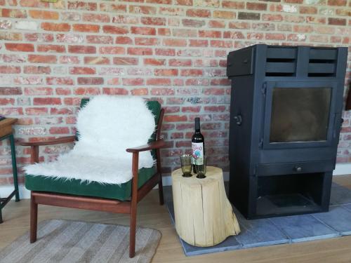 a room with a fireplace and a chair and a bottle of wine at Vakantiewoning-deblinker in Sint-Laureins