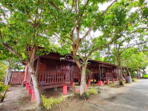un edificio de madera con mesas rojas y árboles en Shell Out Cenang Beach Resort, en Pantai Cenang