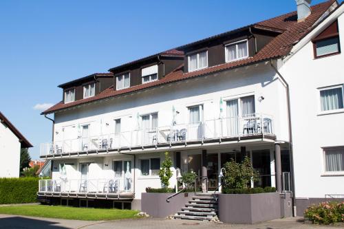 a large white building with balconies and stairs at Hotel Löwen in Meckenbeuren
