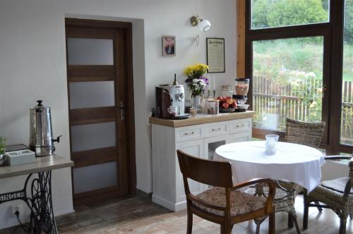 a kitchen with a white table and chairs and a window at Penzion Pod Rozhlednou in Janov