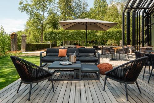 a patio with a table and chairs and an umbrella at Château de Vignée in Rochefort