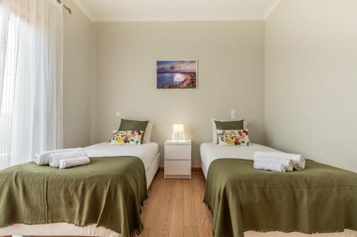 a bedroom with two beds with green sheets at Apartamento 7 Mares com 2 Quartos in Sagres