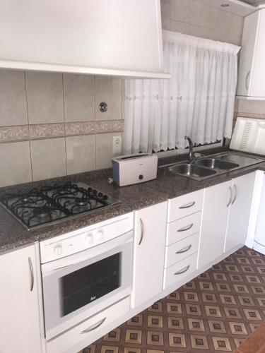 a white kitchen with a sink and a stove at Casa Lola Principe in Geres