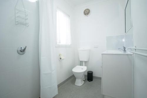 a white bathroom with a toilet and a sink at Bundaberg Park Village in Bundaberg