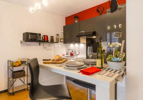 une cuisine avec une table avec des assiettes et des verres à vin dans l'établissement Grünewald Colmar - Studio 2 pers - Parking, à Colmar