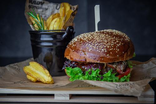 a hamburger and french fries on a wooden board at Hotel ZAWRAT Ski Resort & Spa in Białka Tatrzanska