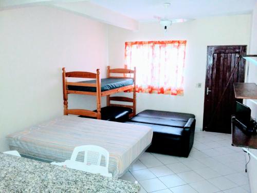 a bedroom with two bunk beds and a chair at kitnets à 300mts Martim de Sá Caragua in Caraguatatuba
