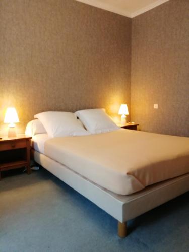 a bedroom with a large white bed with two lamps at Le casse noisettes in Gourin