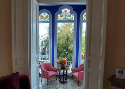 a room with three windows and a table and chairs at Hotel Noucentista in Sitges