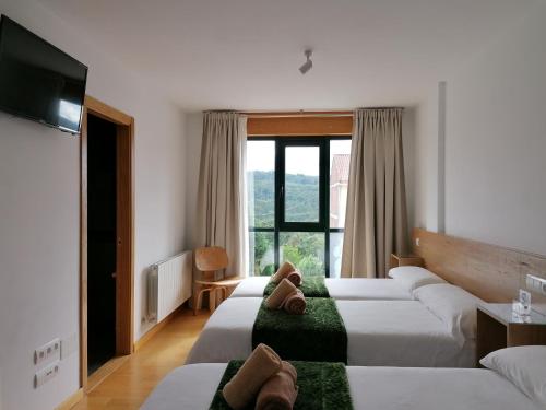 a hotel room with three beds and a television at PENSION ROSELLA in O Pedrouzo
