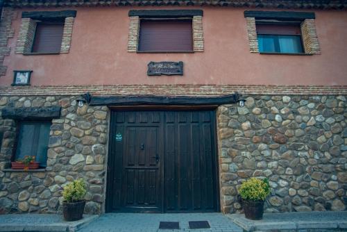 a building with a green door and a stone wall at Casa Rural El Labriego in Corral de Ayllón