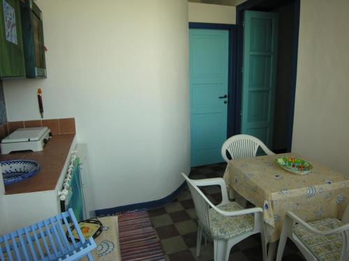 a kitchen with a table and chairs and a blue door at Vulcanoconsult Appartamenti Spiaggia in Lipari