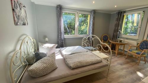 a room with a bed with chairs and windows at Dünenhaus Seensucht in Thiessow
