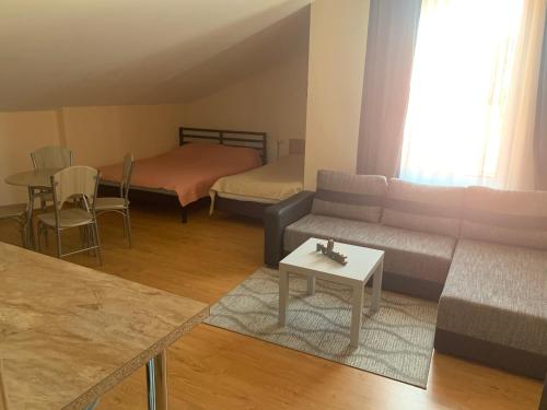 ein Wohnzimmer mit einem Sofa, einem Bett und einem Tisch in der Unterkunft Perlos apartamentai 13 butas in Birštonas