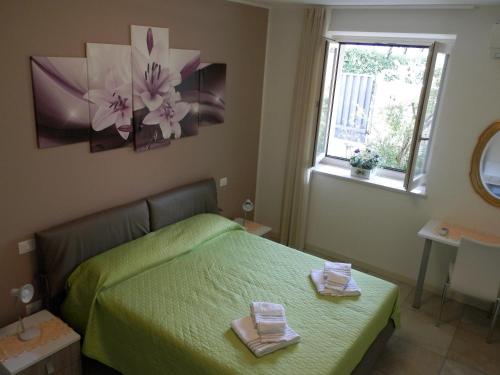 una camera da letto con un letto verde con due asciugamani di Appartamenti Rossini a Bardolino