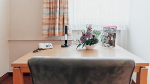 a desk with a telephone and a vase of flowers on it at Avantgarde Hotel in Hattingen