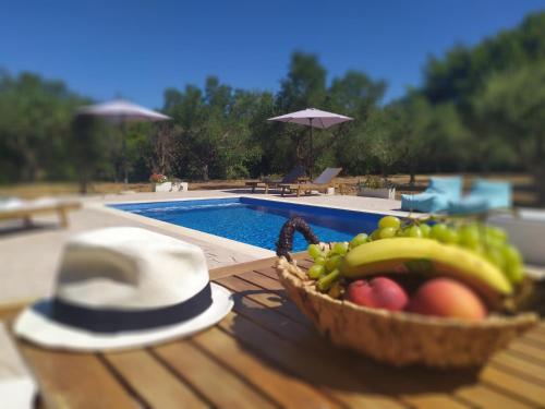 a basket of fruit on a table next to a pool at Loggos Summer House in Vasilikos