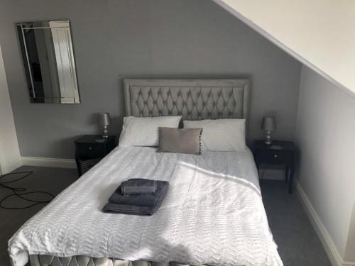 a bed with a white comforter and a mirror at Bay View Apartment in Newbiggin-by-the-Sea