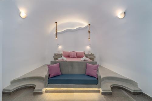 a bedroom with a bed with pink and blue pillows at Cally Cave House in Fira