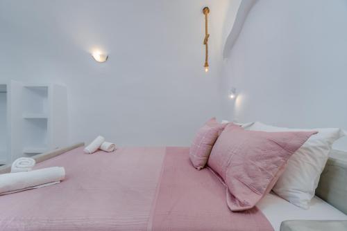 a pink pillow sitting on top of a bed at Cally Cave House in Fira