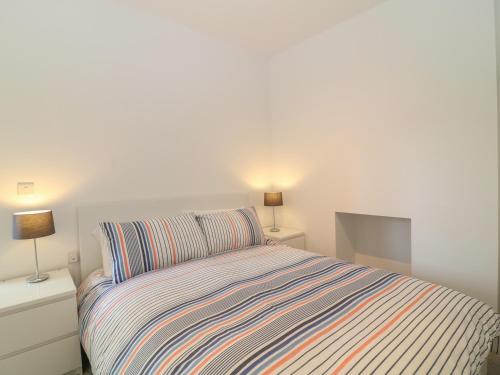 um quarto com uma cama com uma colcha listrada e 2 candeeiros em Samphire em Teignmouth
