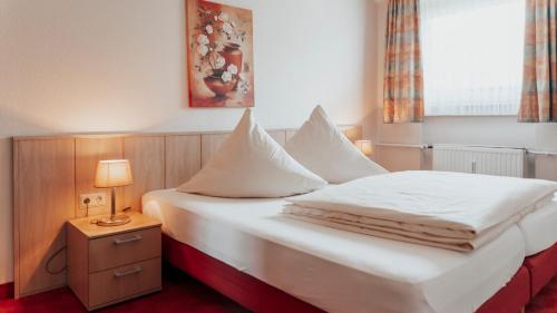ein Schlafzimmer mit einem Bett mit weißer Bettwäsche und einer Lampe in der Unterkunft Avantgarde Hotel in Hattingen