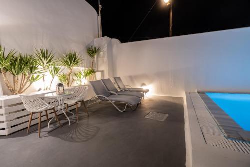 a patio with a table and chairs and a pool at Cally Cave House in Fira