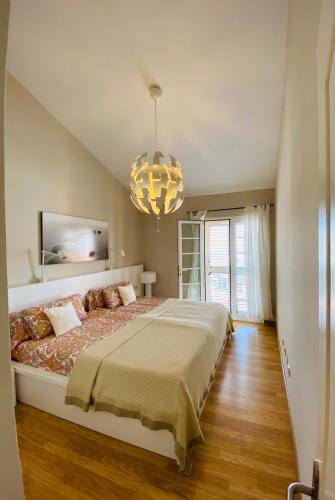 a bedroom with a large bed and a chandelier at Olivia Holidayhouse Maspalomas in Maspalomas