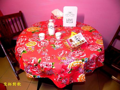 a table with a red table cloth with flowers on it at Ting Yi B & B in Taitung City