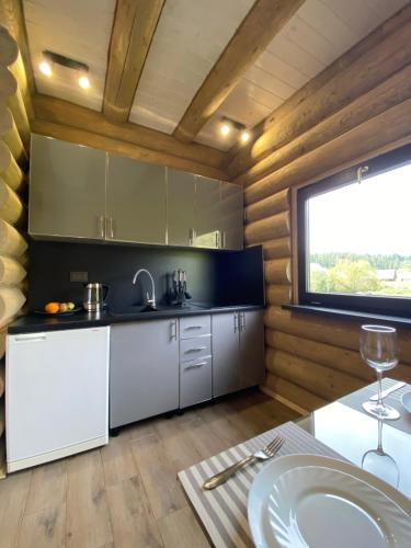 uma cozinha com armários brancos, uma mesa e uma janela em Чотири сезони em Izki