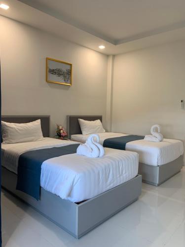 two beds in a hotel room with towels on them at Icare Residence & Hotel in Bangkok