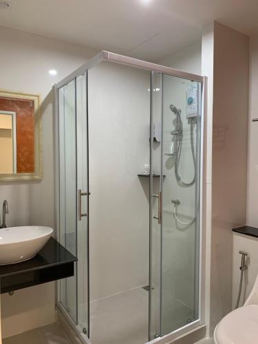 a glass shower in a bathroom with a sink at Icare Residence & Hotel in Bangkok