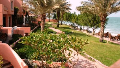 a view of a resort with palm trees and the ocean at Seashell Julai'a Hotel & Resort Family resort in Al Qulay‘ah